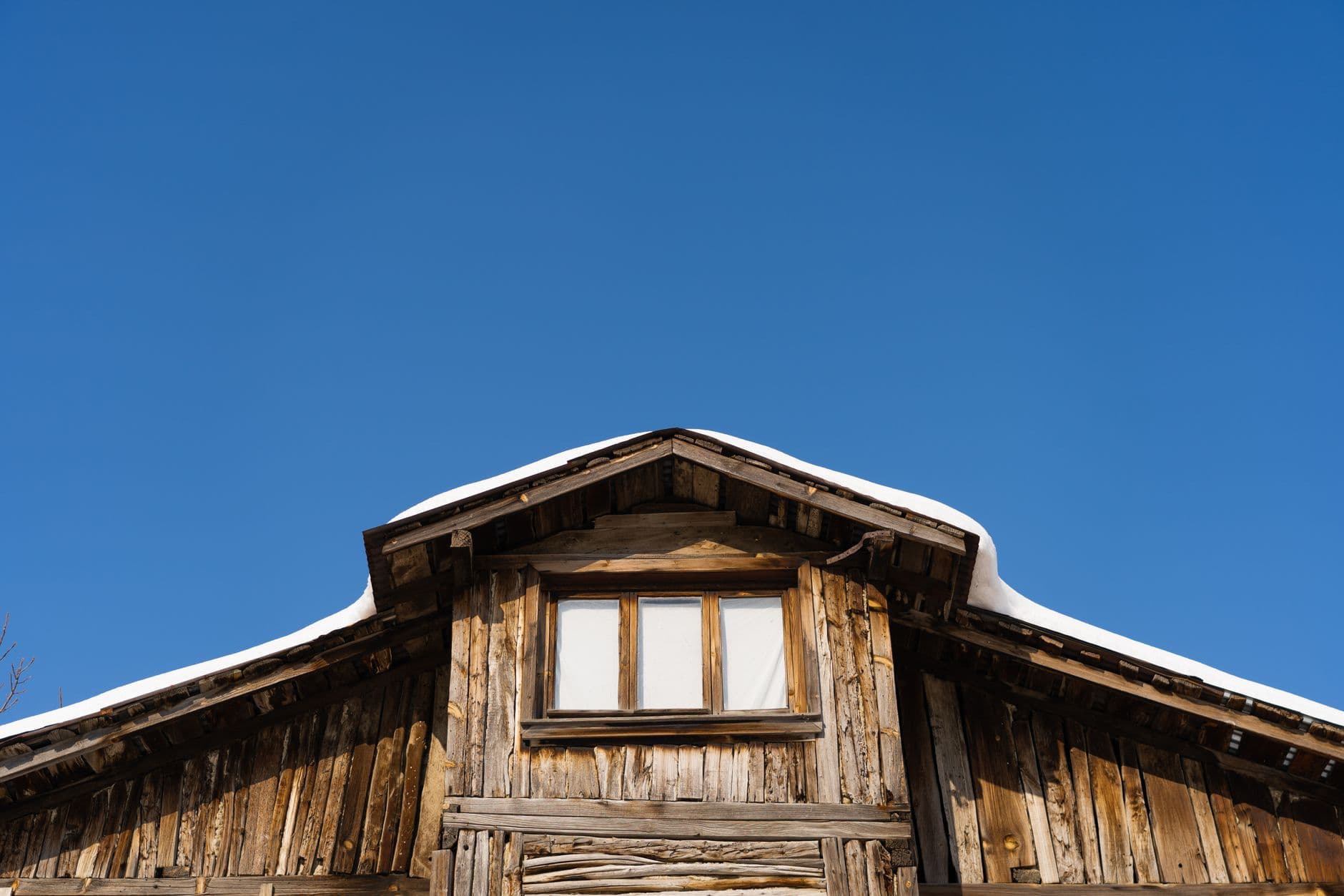 Low angle view of a wooden cabin roof with snow and clear blue sky in Mudurnu, Türkiye.